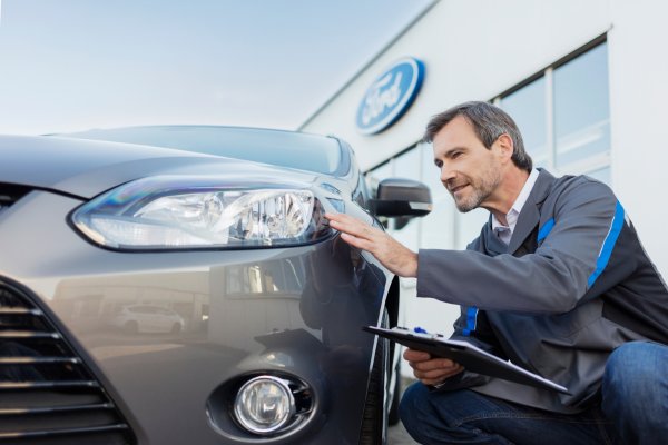 Mann inspiziert Fahrzeug am Parkplatz
