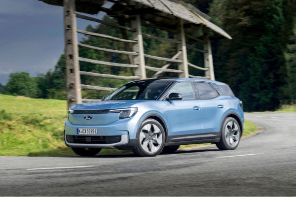 Ford Explorer in blau unterwegs auf Strasse mit Holzzaun im Hintergrund