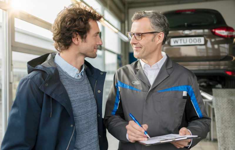 Dienstleistungen Serviceberater und Kunde stehen in Ford-Werkstatt
