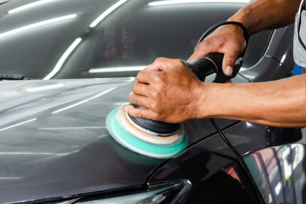 Mechaniker poliert Lack eines Fahrzeugs