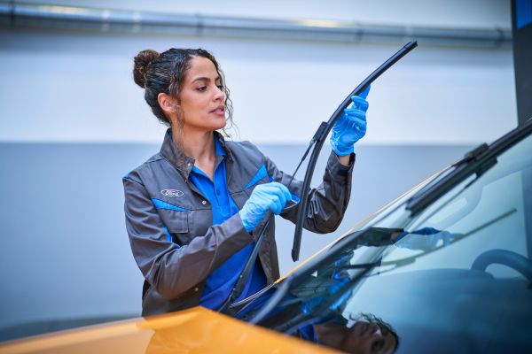 Mechanikerin inspiziert Scheibenwischer eines Fahrzeugs