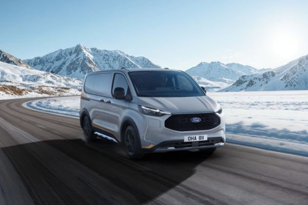 Ford Transit Transporter fährt durch Schneelandschaft mit Bergen im Hintergrund
