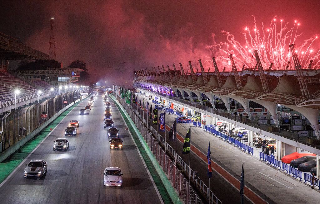Reta do Circuito de Interlagos com vários Ford Mustang enfileirados e fogos de artifício ao fundo
