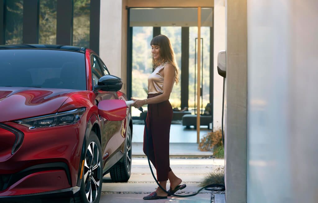 Mulher acoplando o carregador elétrico no Ford Mustang Mach-E vermelho