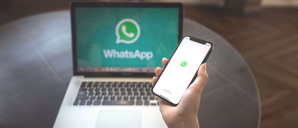 Computador e celular, ambos exibindo a logo do WhatsApp
