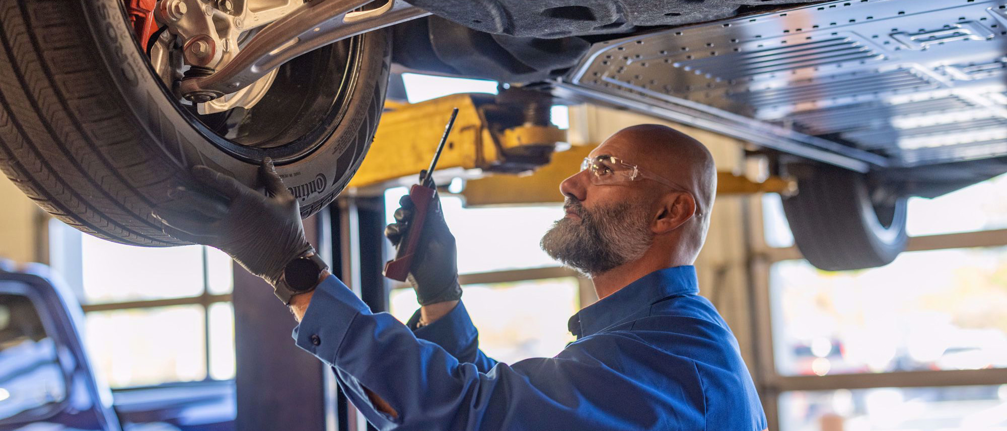 Trabajador revisando una llanta debajo de un vehículo Ford