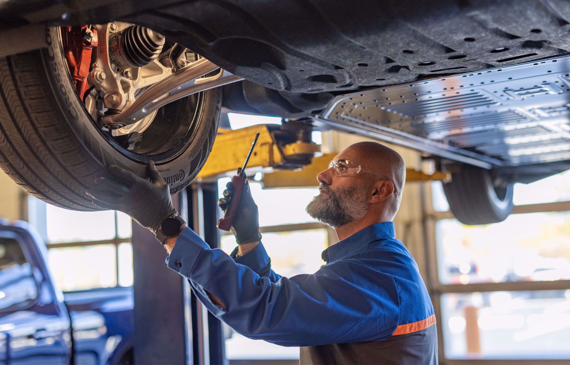 Trabajador revisando una llanta debajo de un vehículo Ford