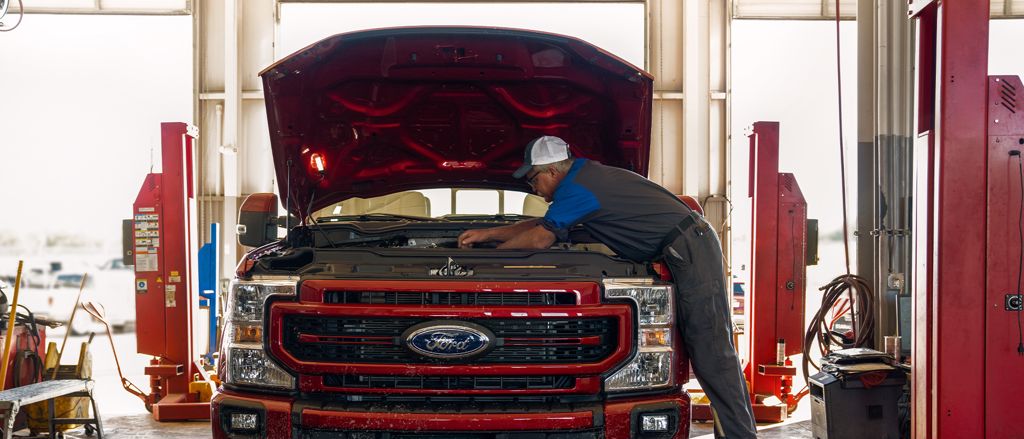 Hombre trabajando con herramientas en el motor de un carro